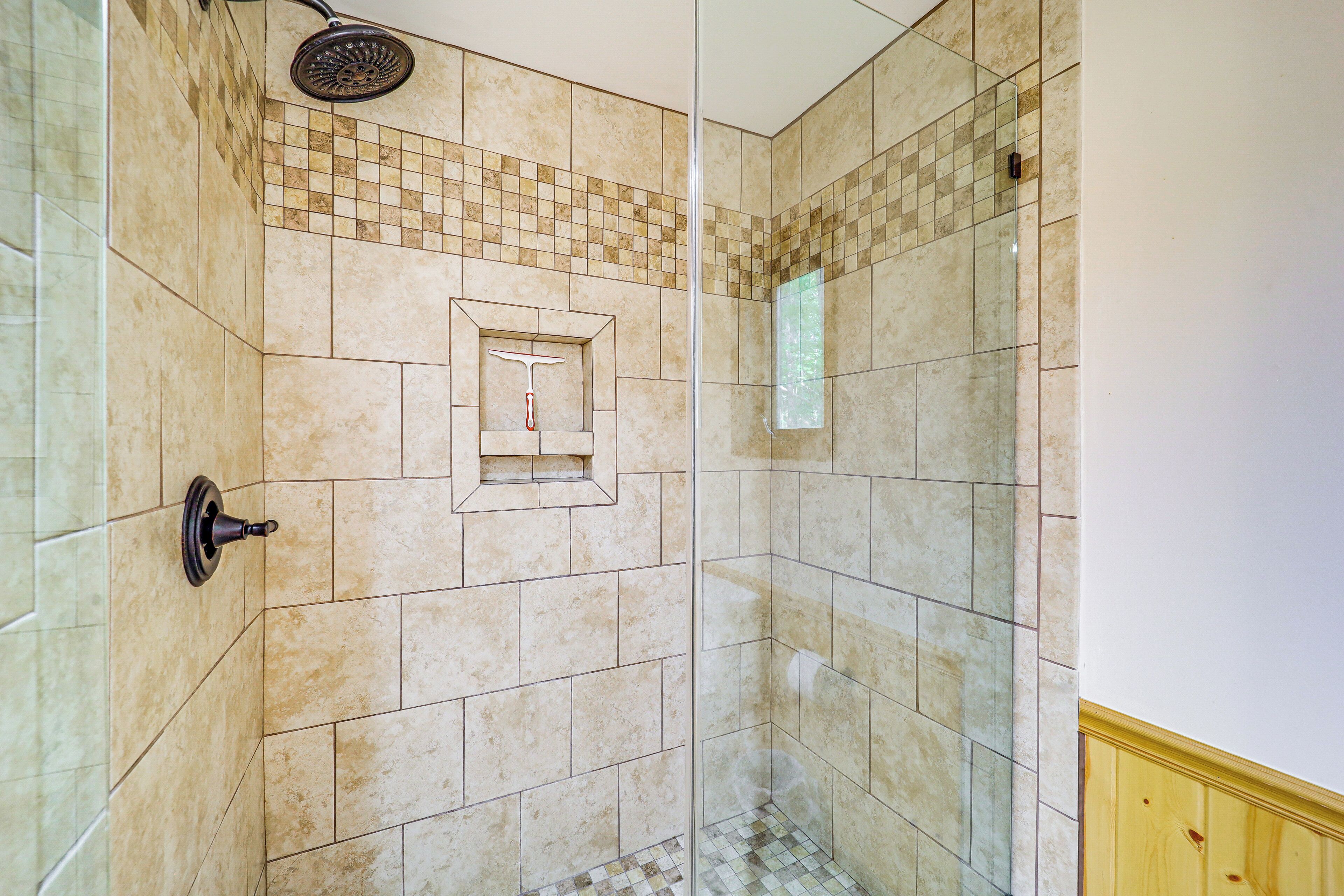 A shower with a glass door, tiled walls, and a showerhead.