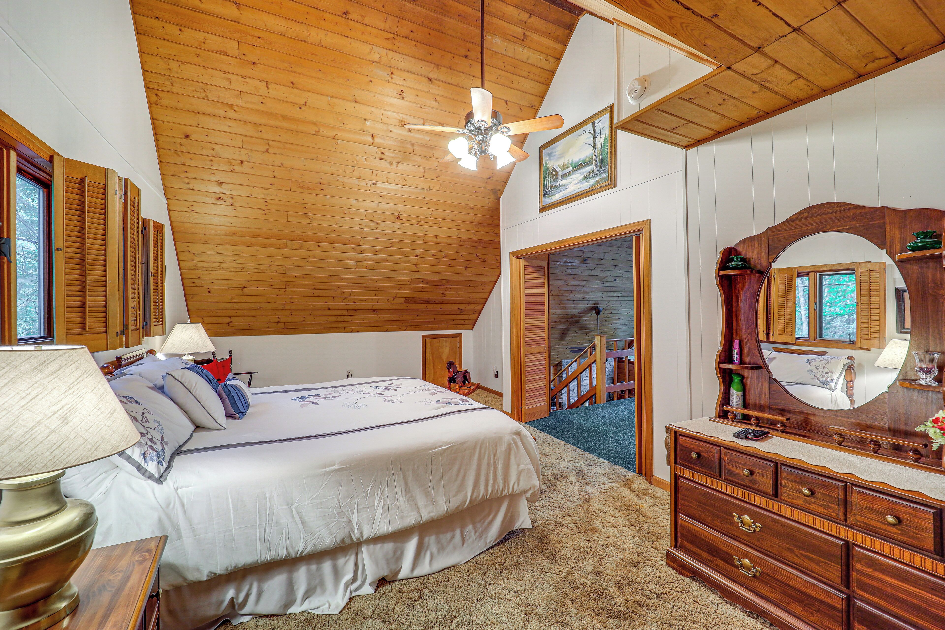 Ein Schlafzimmer mit Holzboden, einem Bett mit weißer Bettwäsche, einem Schminktisch mit Spiegel und einer Treppe, die in einen anderen Raum führt.