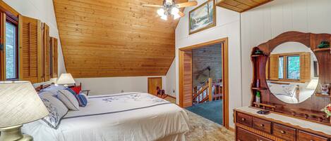 Ein Schlafzimmer mit Holzboden, einem Bett mit weißer Bettwäsche, einem Schminktisch mit Spiegel und einer Treppe, die in einen anderen Raum führt.