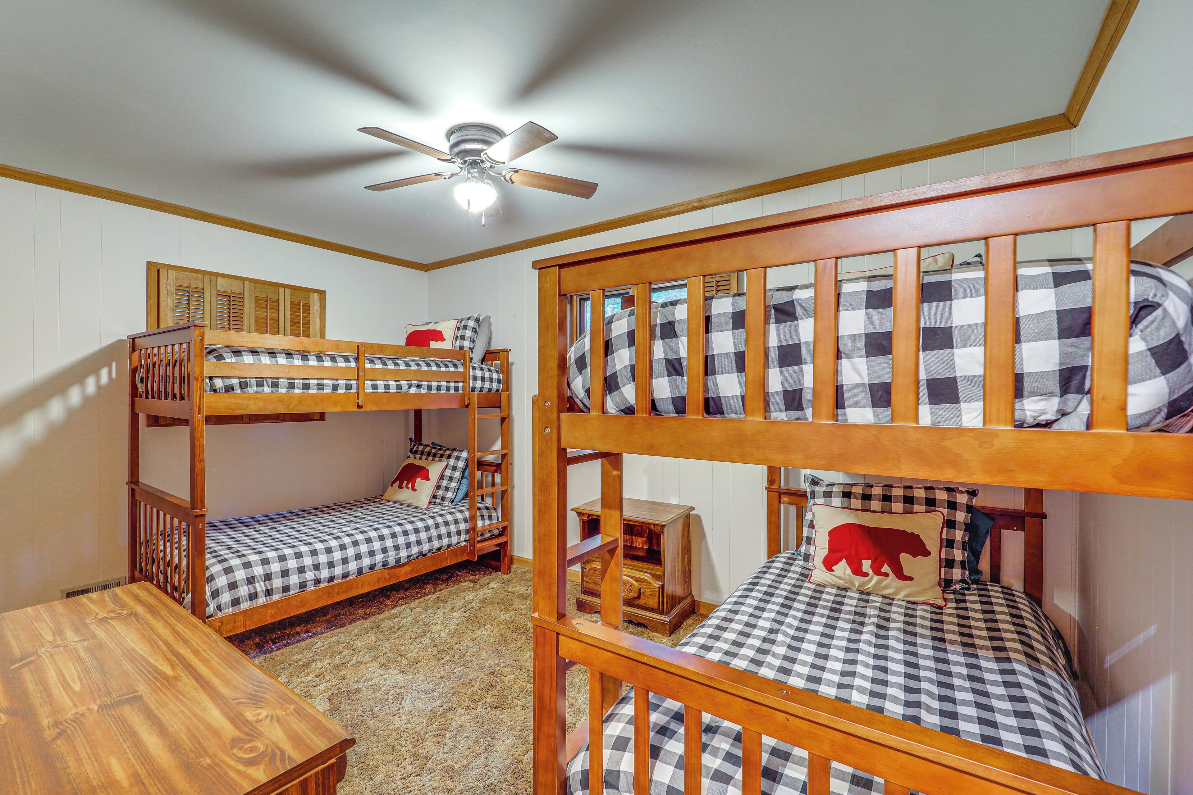 A room with two bunk beds, a ceiling fan, and a small wooden table.