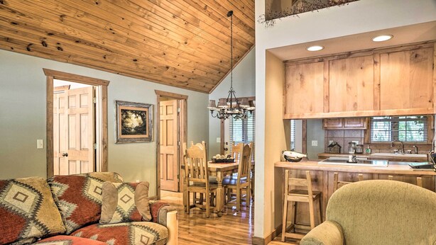 A cozy living room with a sofa, a coffee table, and a dining area with a table and chairs. - Screened Deck: Cozy Branson West Cabin! (Branson West)