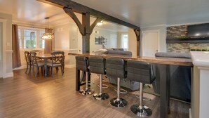 A modern kitchen with a wooden bar and four bar stools. - Waterfront Home w/ Hot Tub in Wrightsville! (Wrightsville)