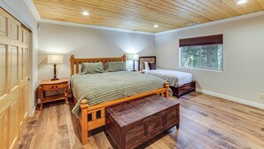 A bedroom with two beds, wooden flooring, a ceiling with wooden beams, a window, and a door.