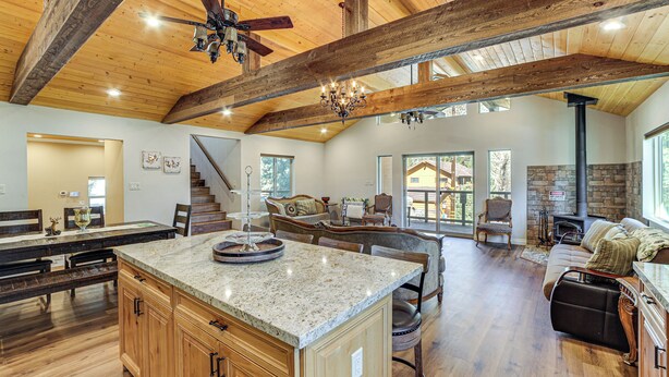 A spacious living area with a large island, wooden beams, a fireplace, and a stone accent wall.