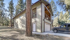 A two-story house with a garage, surrounded by trees.