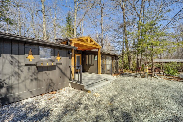 A cabin with a wooden porch, a small deck, and a gravel driveway. - Near Lake + Trails: Rustic Newland Cabin w/ Deck! (Newland)