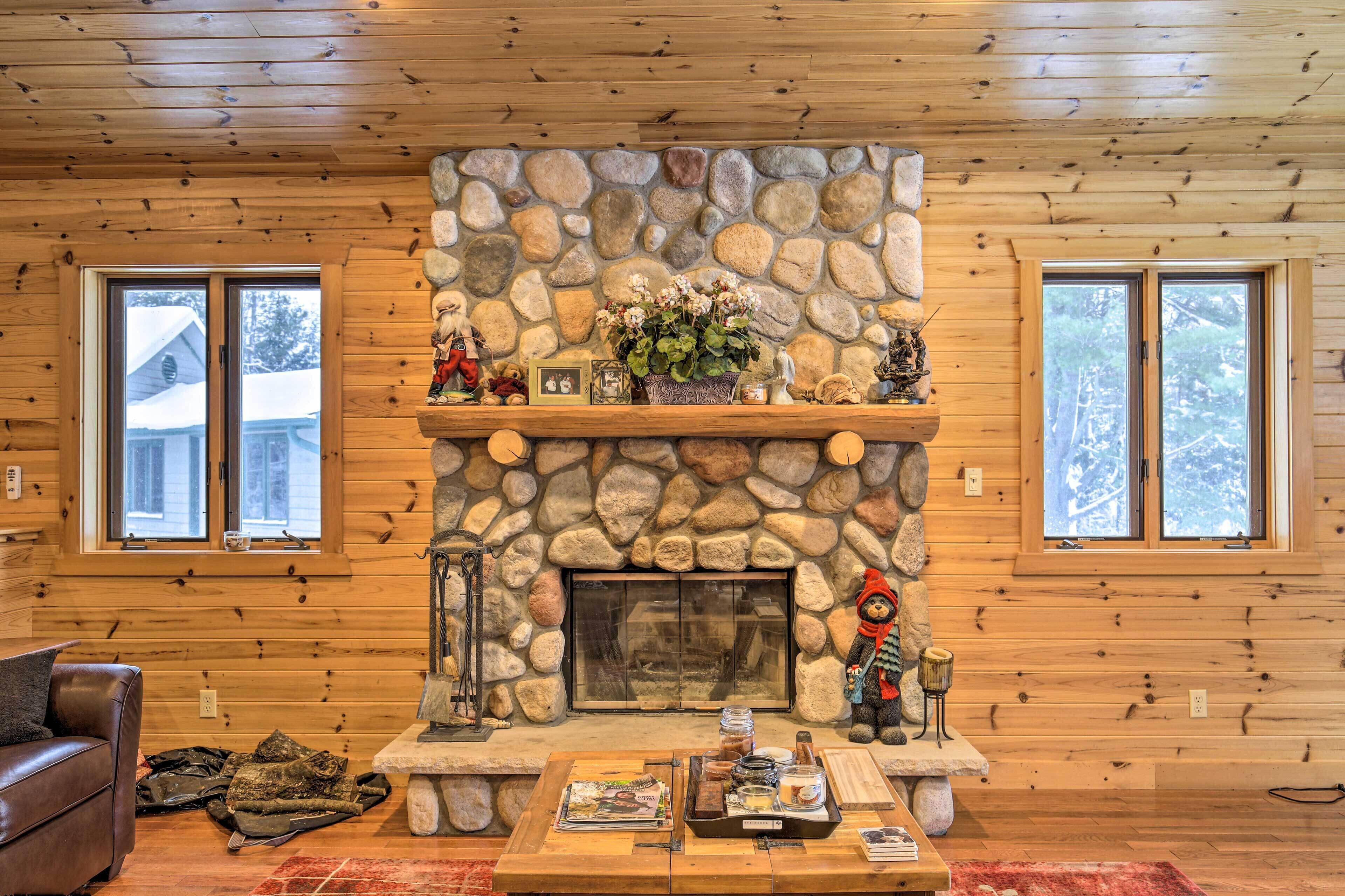 Un intérieur de chalet chaleureux avec une cheminée en pierre, des murs en bois et un canapé en cuir.