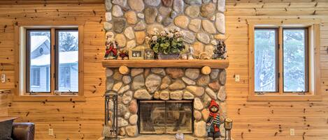 Un intérieur de chalet chaleureux avec une cheminée en pierre, des murs en bois et un canapé en cuir.