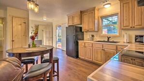 A modern kitchen with wooden cabinets, a stainless steel refrigerator, and a dining area with a round table and chairs.