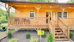 A wooden cabin with a porch, outdoor seating, and a staircase leading to the entrance.