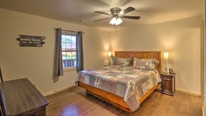 A bedroom with a wooden bed, a ceiling fan, a nightstand, and a window with curtains.