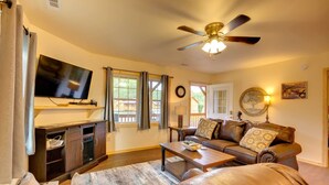 A living room with a television, a ceiling fan, a sofa, a coffee table, and a wooden cabinet.