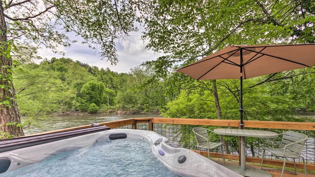 A hot tub on a deck with a view of a river and forest.