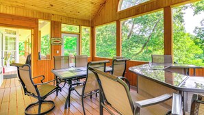 A wooden deck with a glass table and chairs, surrounded by large windows offering a view of greenery. - Lake Cumberland Retreat w/ Deck & Views! (Jamestown)