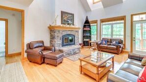 A spacious living room with a stone fireplace, leather sofas, and a glass coffee table. - Lake Cumberland Retreat w/ Deck & Views! (Jamestown)