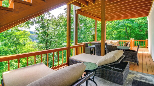 A wooden deck with wicker furniture, a table, and a view of a forested area. - Lake Cumberland Retreat w/ Deck & Views! (Jamestown)
