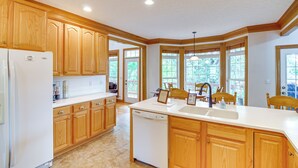 A spacious kitchen with wooden cabinets, a white refrigerator, a dishwasher, and a large window providing natural light. - Lake Cumberland Retreat w/ Deck & Views! (Jamestown)