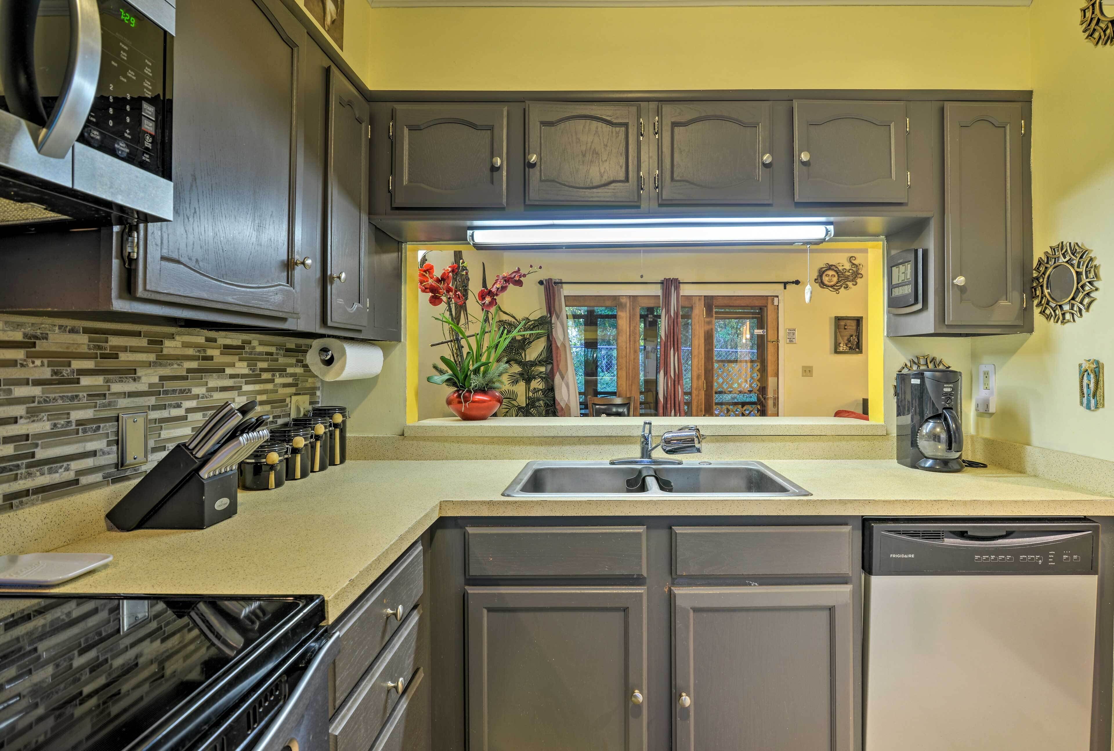 A kitchen with dark cabinets, a stainless steel microwave, a dishwasher, and a sink.