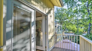 A wooden deck with a glass door leading to a covered porch. - 1 Block to Shore: Family Condo in Myrtle Beach! (Myrtle Beach)