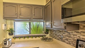A kitchen with gray cabinets, a microwave, a toaster, and a window with blinds. - 1 Block to Shore: Family Condo in Myrtle Beach! (Myrtle Beach)