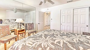 A bedroom with a bed, a ceiling fan, a desk with a lamp, a chair, and a large mirror. - Spacious & Private Wine Country Villa w/ View (Temecula)