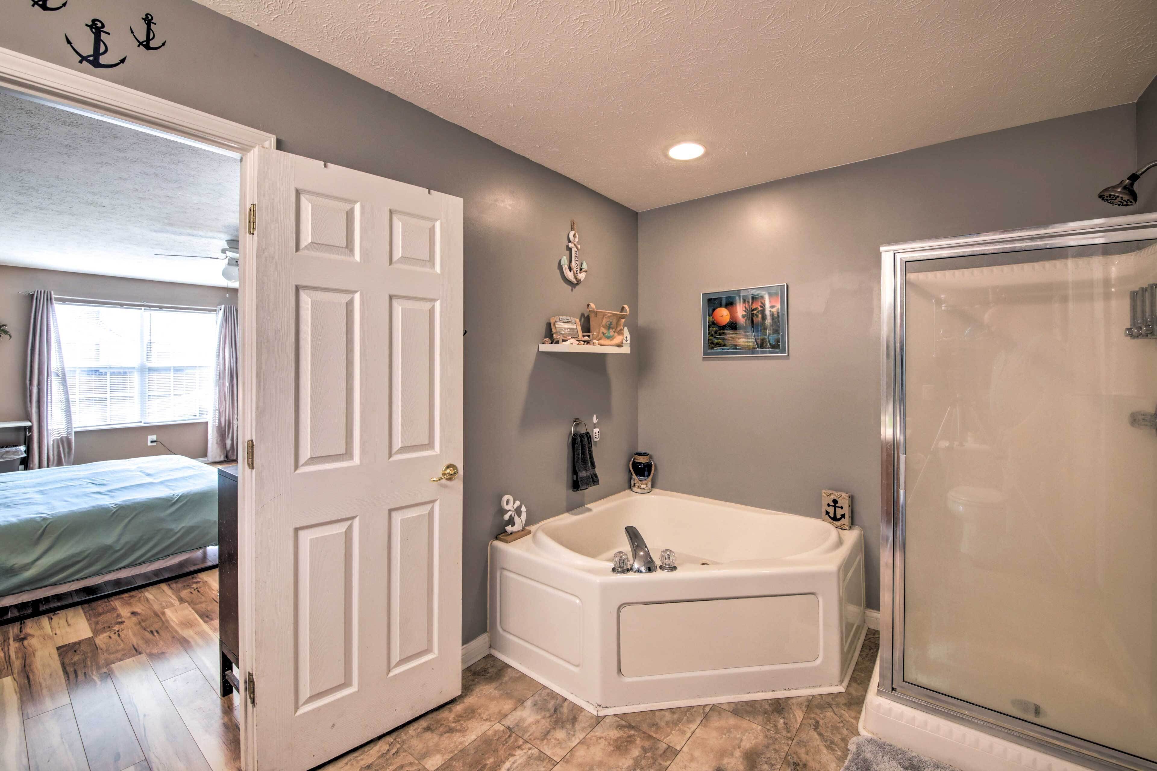 A bathroom with a bathtub, shower, and a door leading to a bedroom.