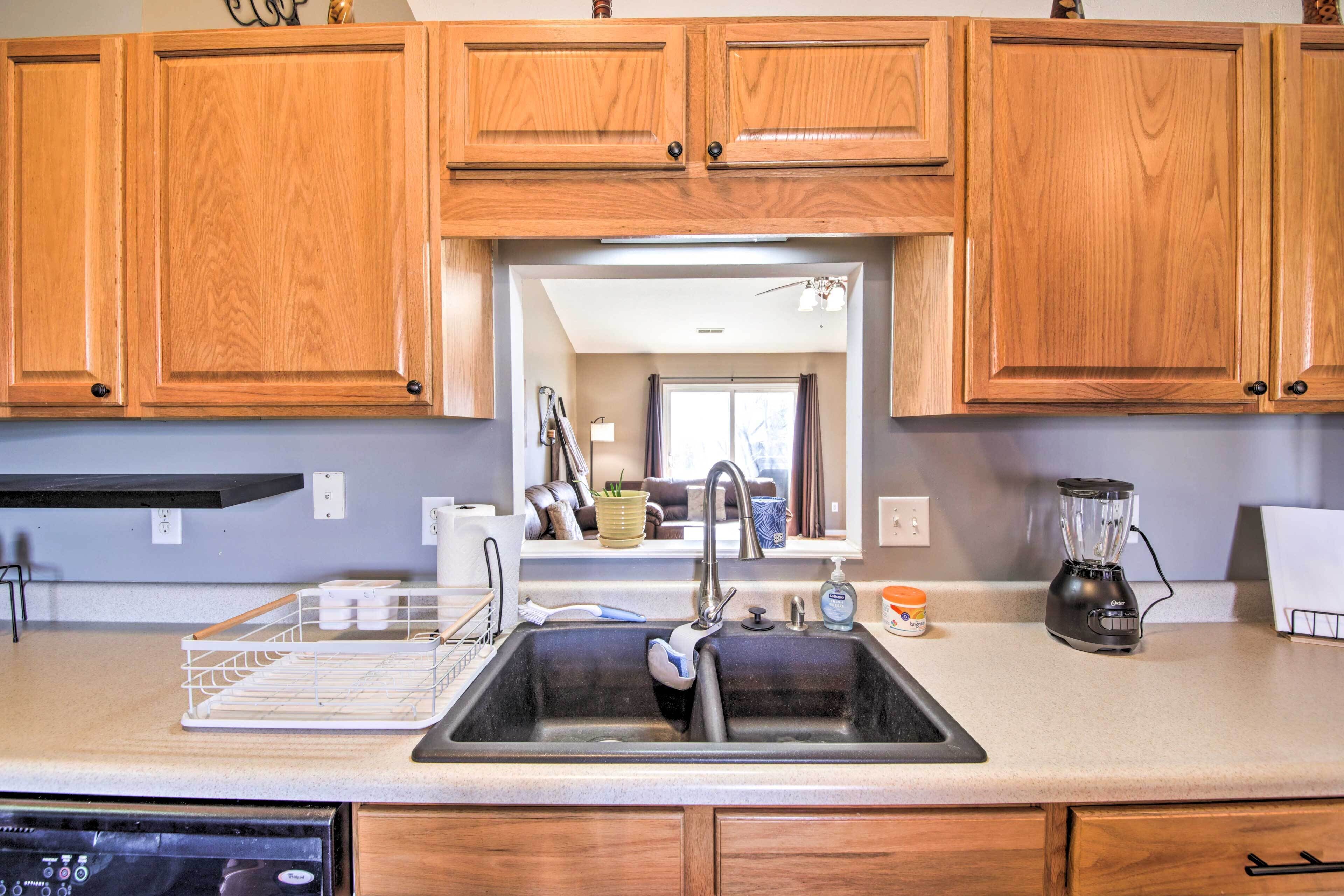 A kitchen with wooden cabinets, a double sink, a dishwasher, and a blender on the counter.