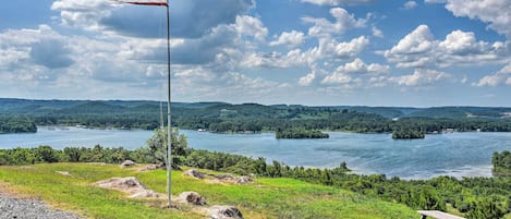 A flagpole with an American flag, a picnic table, and a lake with islands in the background.