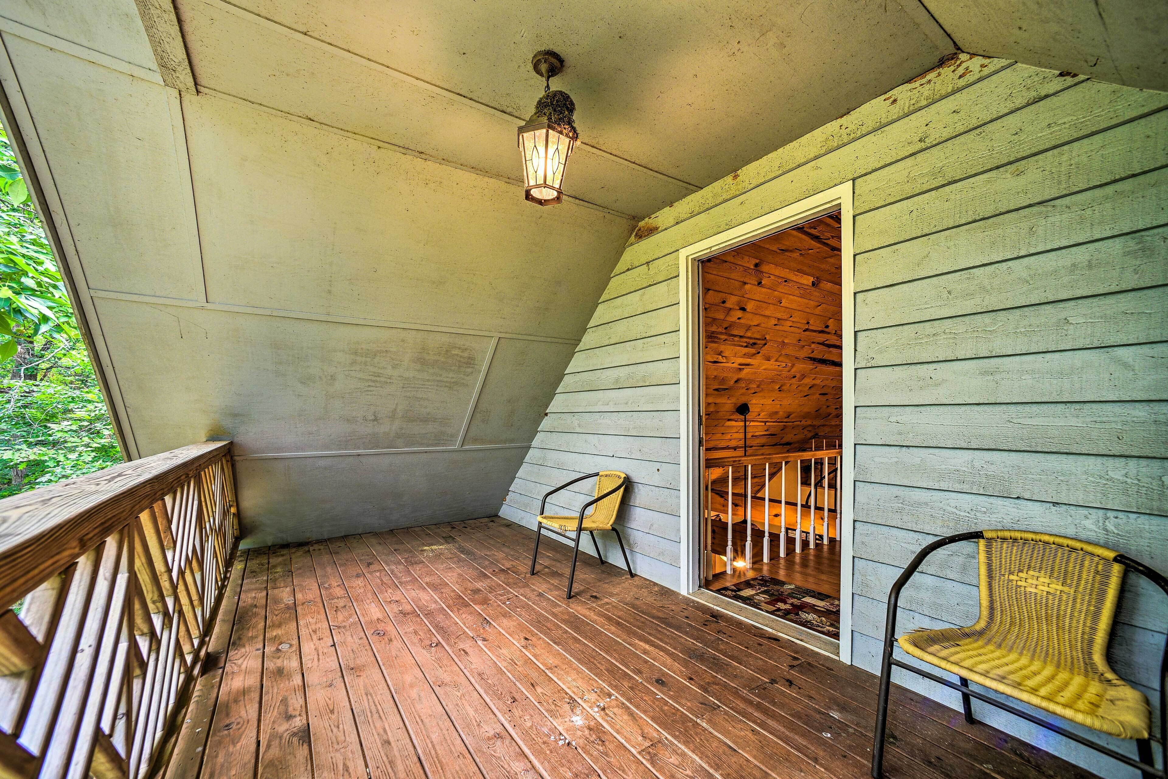 A wooden deck with a wooden railing, a single chair, and a lantern.