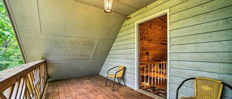 A wooden deck with a wooden railing, a single chair, and a lantern.