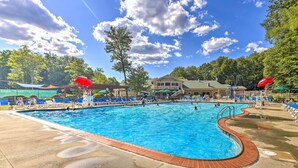 Ein Swimmingpool mit blauem Wasser, umgeben von Liegestühlen und Sonnenschirmen.