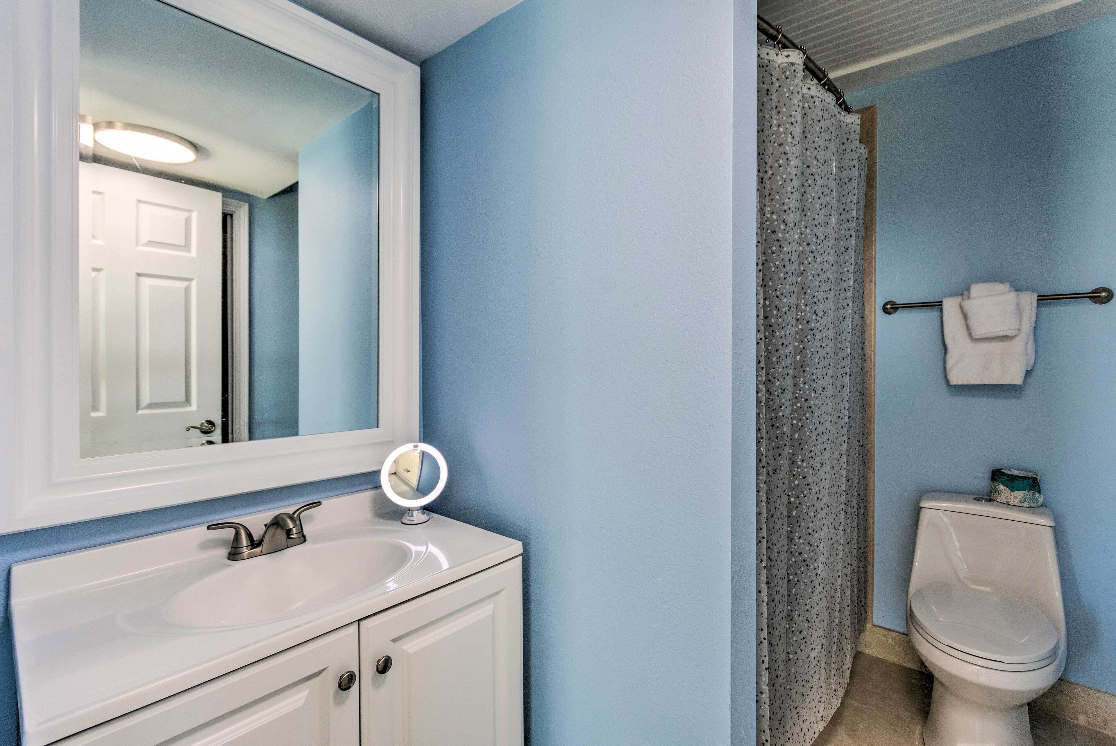 A bathroom with a white sink, a mirror, a toilet, and a shower curtain.