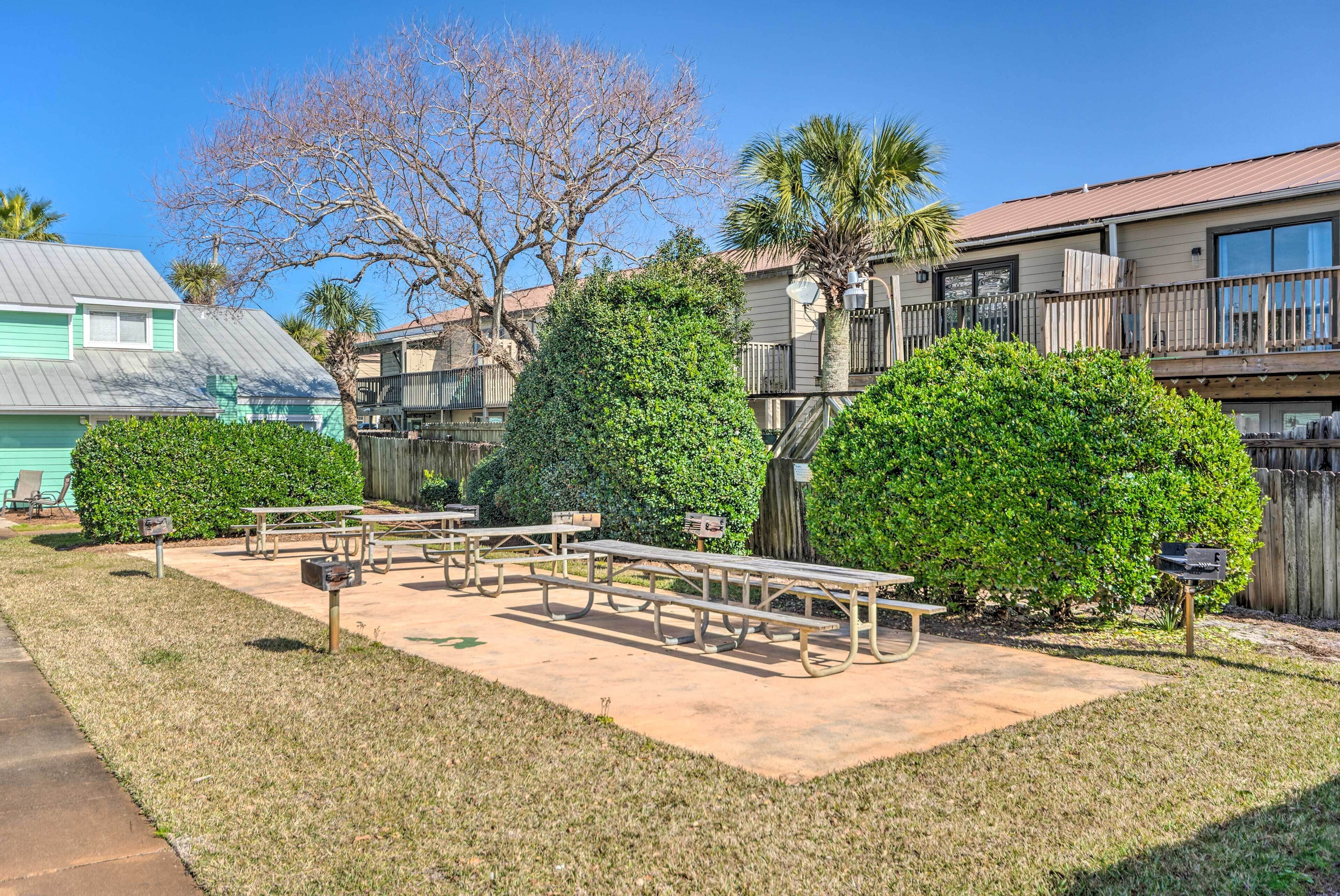 A courtyard with picnic tables, a small lawn, and a wooden fence.