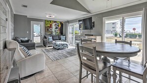 A spacious living room with a dining area, a ceiling fan, and a TV mounted on the wall. - Vibrant Family Condo: 100 Feet to Private Beach! (Miramar Beach)