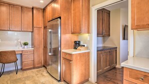 A kitchen with wooden cabinets, a stainless steel refrigerator, a coffee maker, and a countertop.