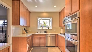 A modern kitchen with wooden cabinets, stainless steel appliances, and a window with a view.