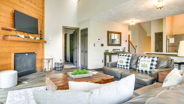 Een moderne woonkamer met een open haard, leren bank en een wandgemonteerde flatscreen-tv.