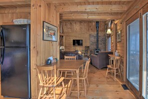 Un interior de madera con una mesa de comedor, sillas, un refrigerador y una chimenea.