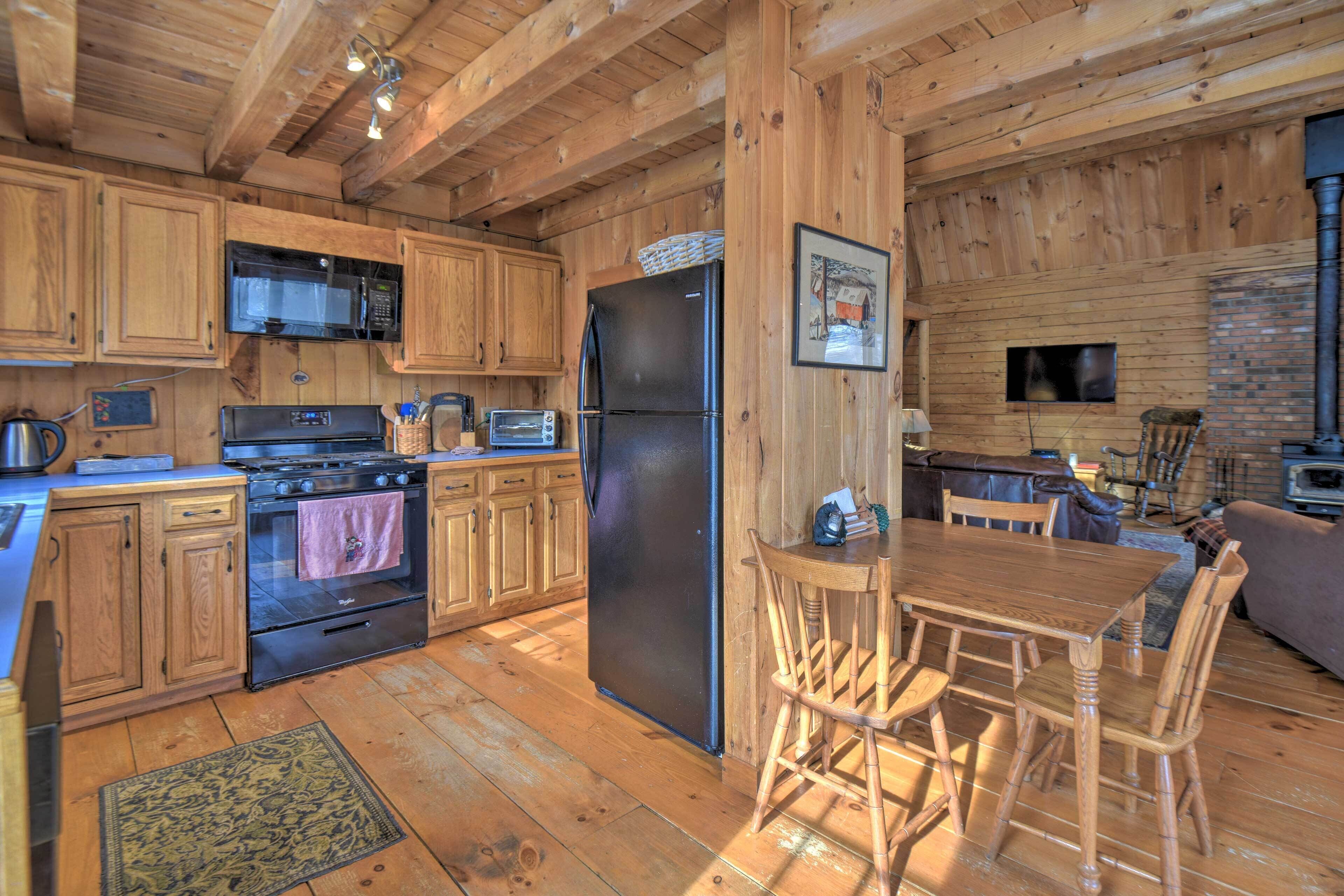 Een houten cabin met een keuken, eethoek en open haard.