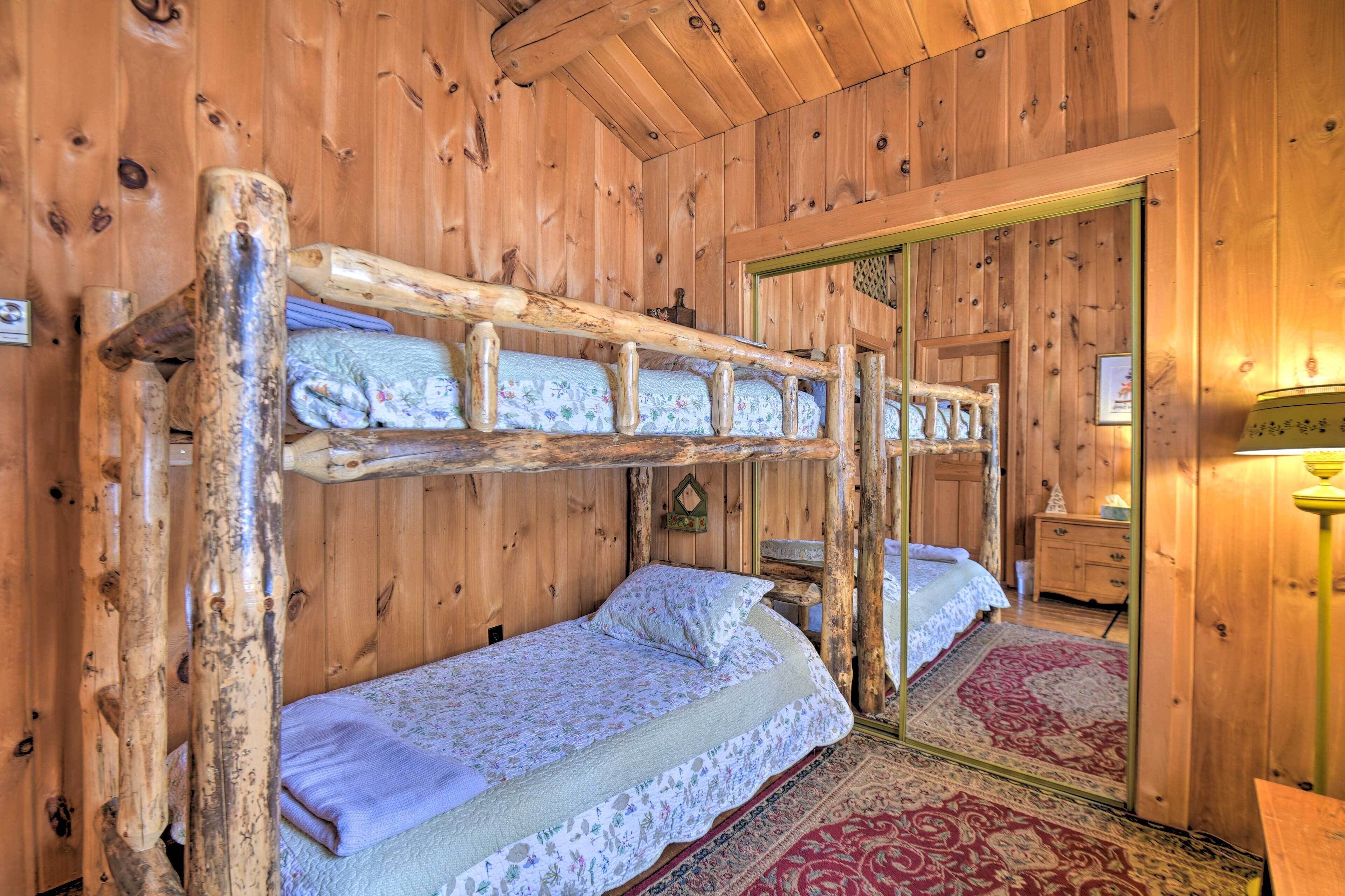 A wooden cabin room with bunk beds, a mirror, a wooden dresser, and a rug.
