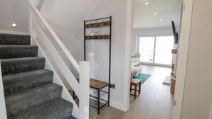 Un escalier dont les marches sont recouvertes d’un tapis gris, menant à un palier.
