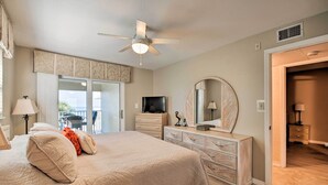 A bedroom with a bed, dresser, TV, and a ceiling fan.