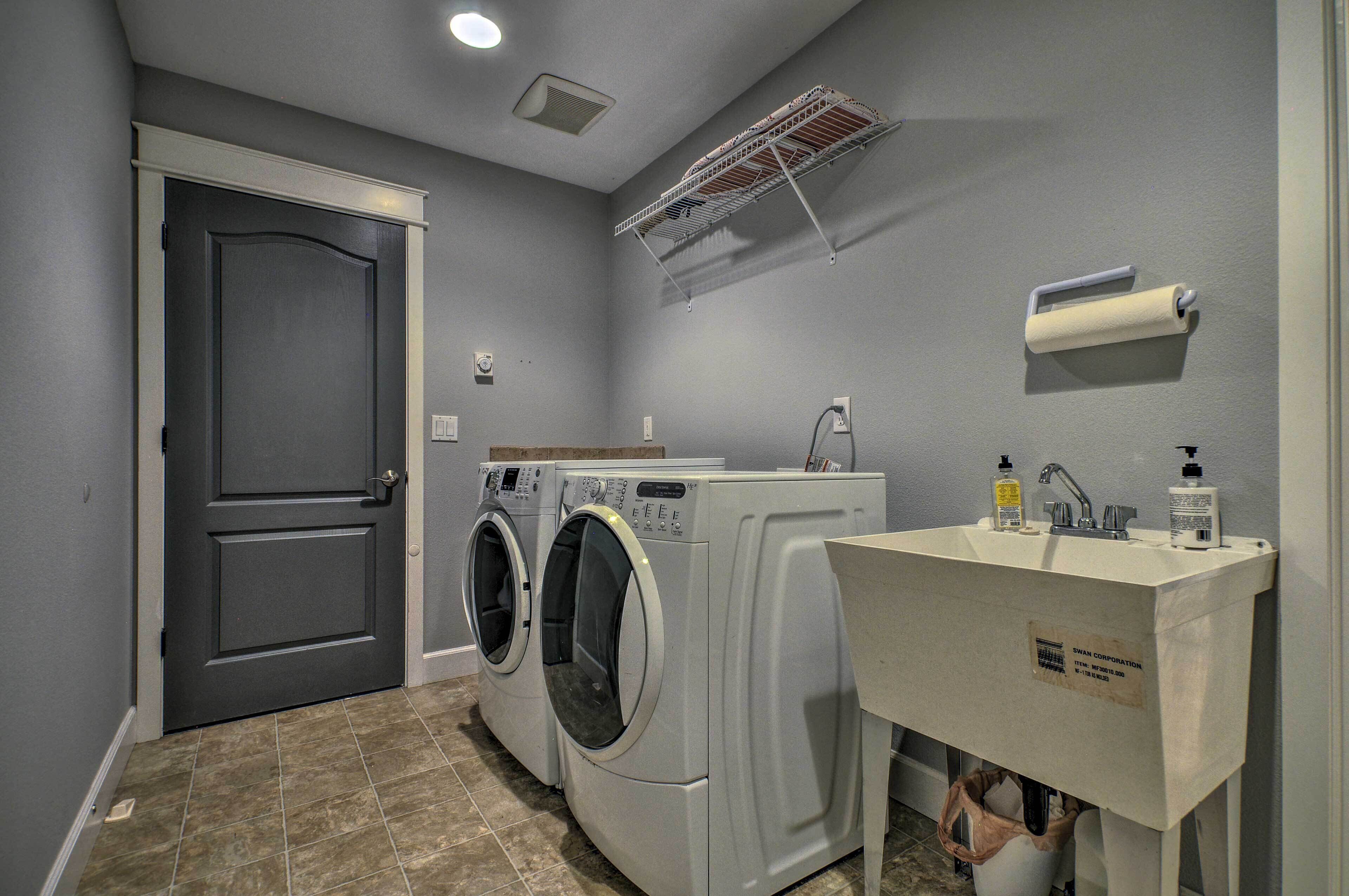 A laundry room with two front-loading washers and a sink with a mirror.