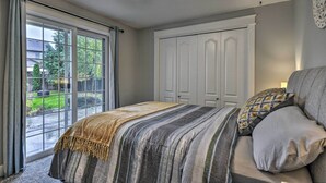 Une chambre avec une grande fenêtre, un lit avec une literie à rayures et une armoire.