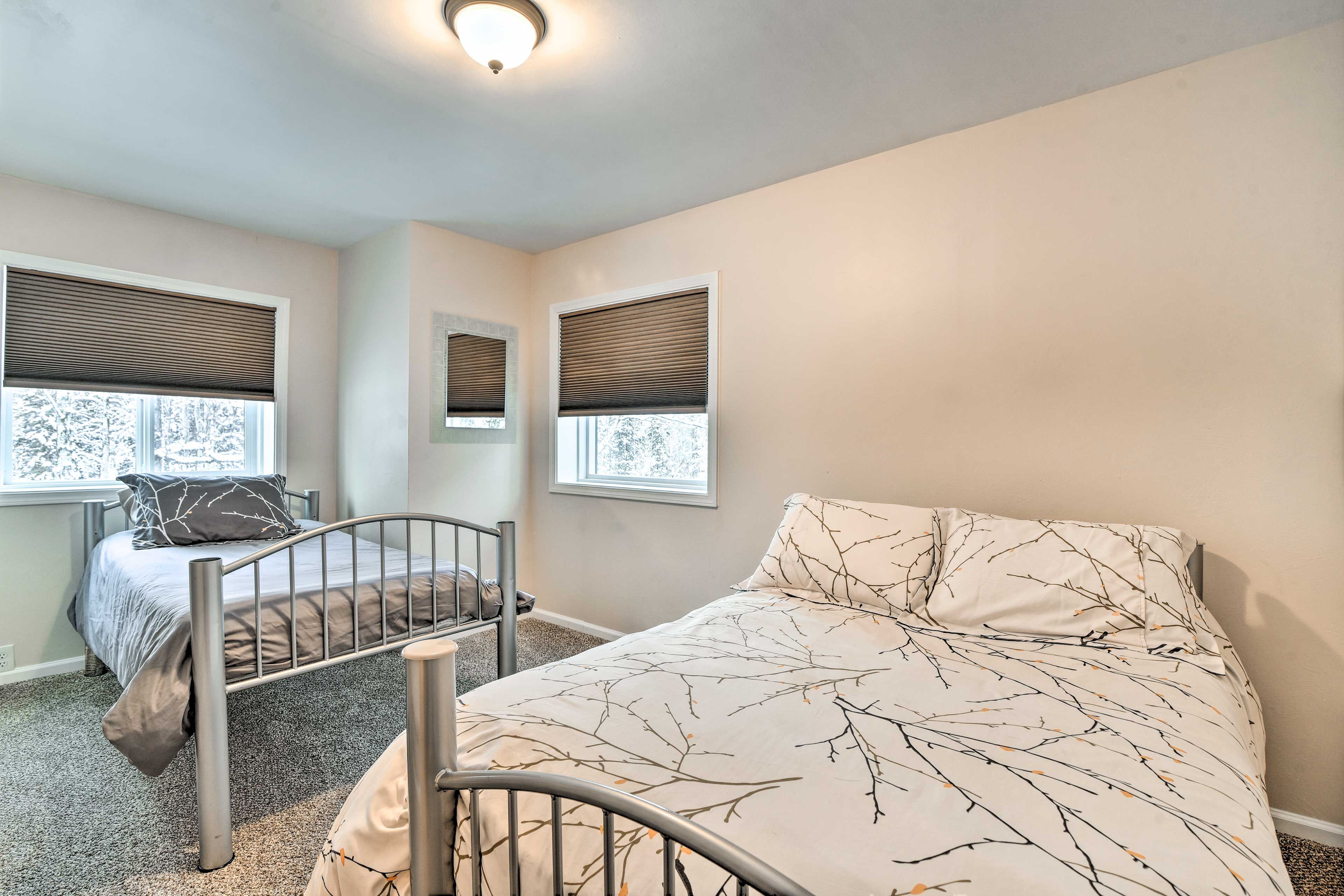A bedroom with two beds, each with a headboard, and a window with blinds.