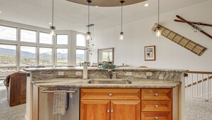 Una cocina con una isla grande, armarios de madera, un fregadero y luces colgantes.