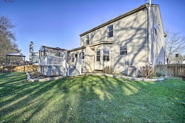 A two-story house with a front porch, a small garden, and a wooden fence.