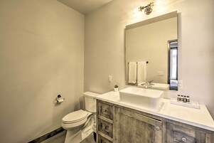 Un baño con inodoro, lavamanos, espejo y tocador de madera.