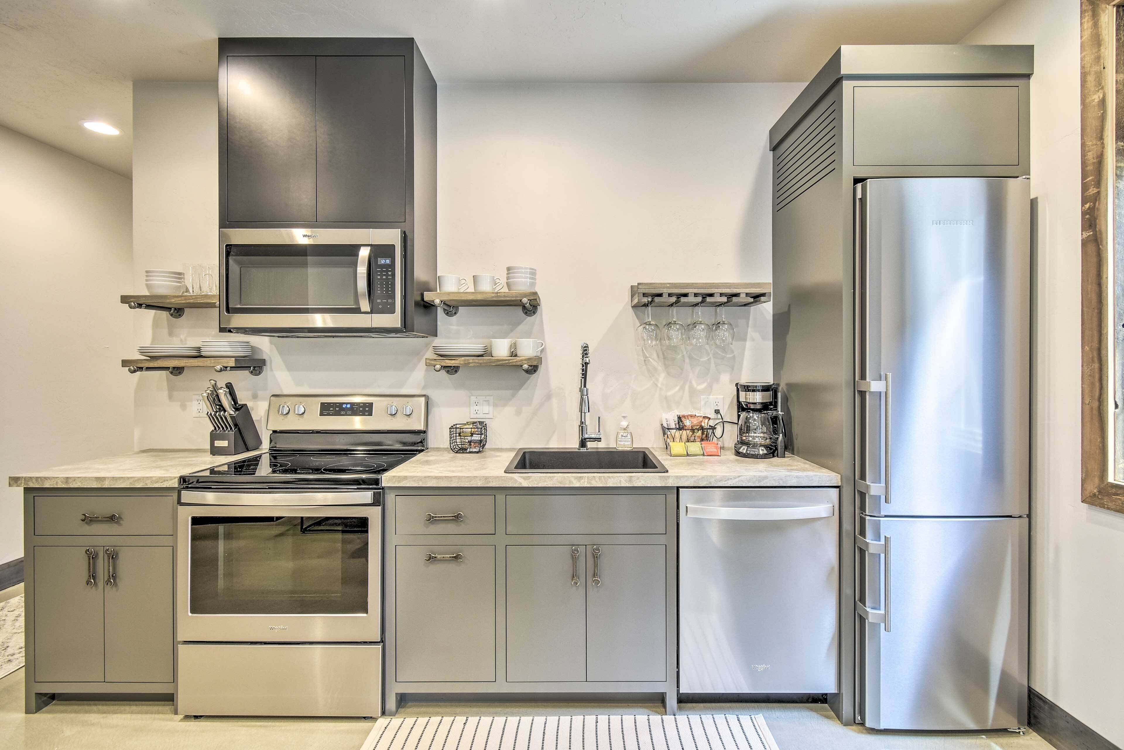 A modern kitchen with stainless steel appliances, including a stove, oven, microwave, and refrigerator. There are built-in cabinets, a countertop with a sink, and a coffee maker.