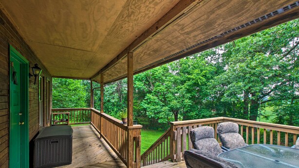 A wooden deck with a glass table and chairs, a green door, and a view of a green landscape. - Pet-friendly VA Home ~ 30 Mi to Shenandoah NP (Weyers Cave)